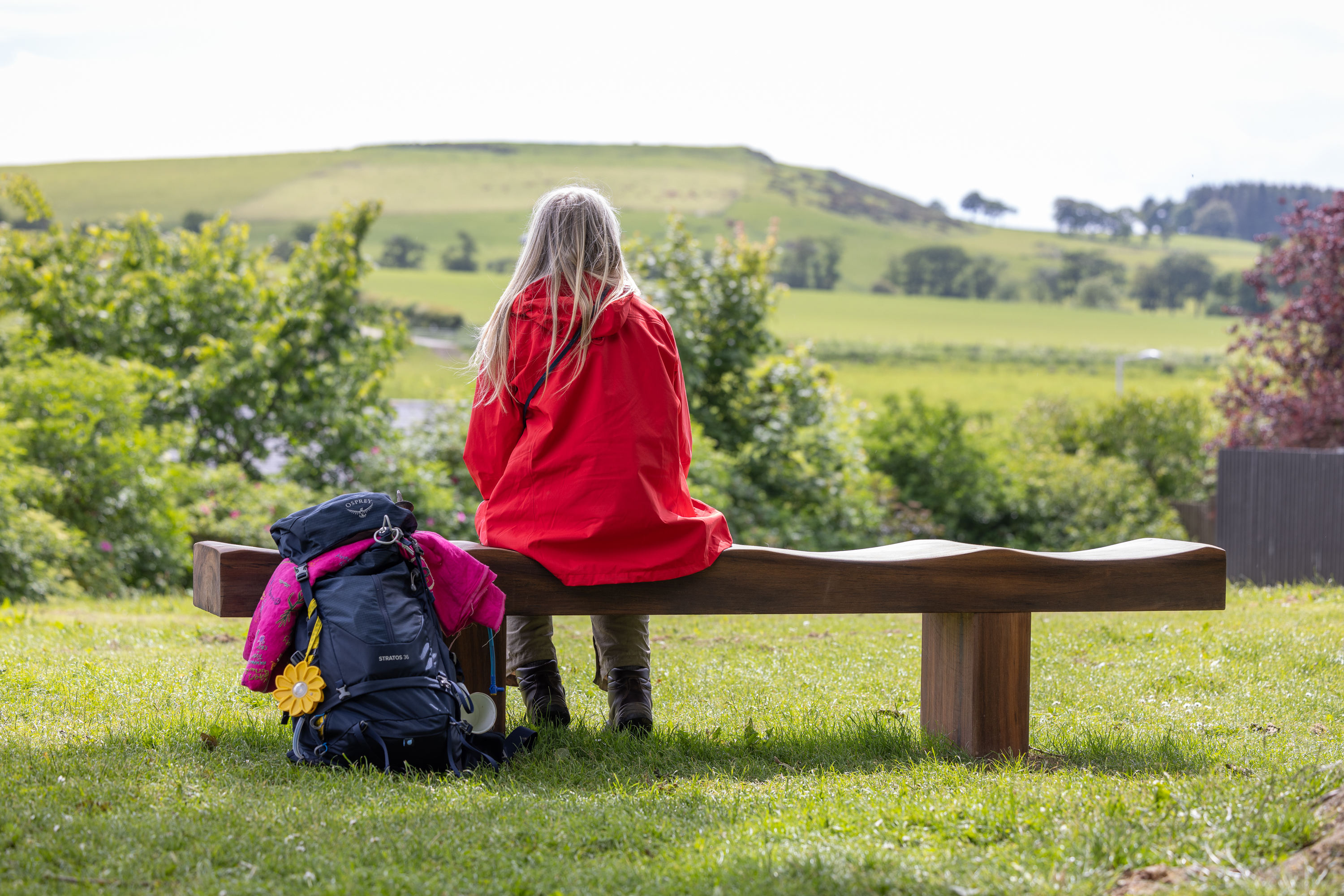 Person sitting in the countryside on a bench reflecting