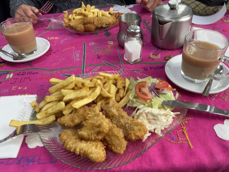 A table with the tablecloth, two cups of tea and two plates of food