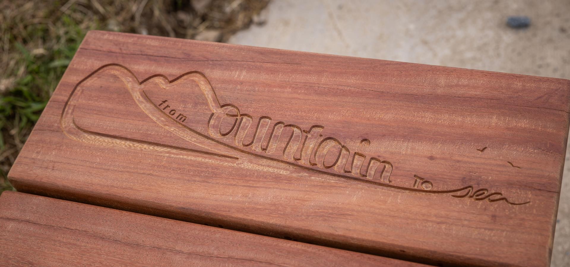 A close up of one of the benches with an engraved From Mountain to Sea design