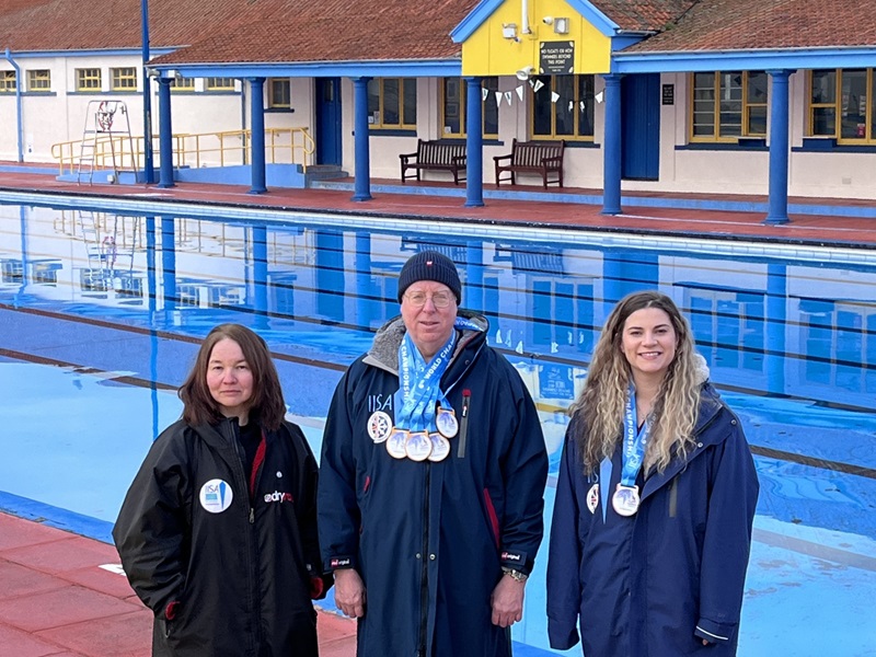 Medal-winning swimmers stand next to Stonehaven Open Air Pool