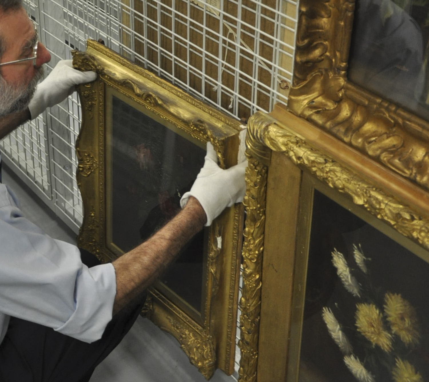 gentleman holding framed painting in storage.