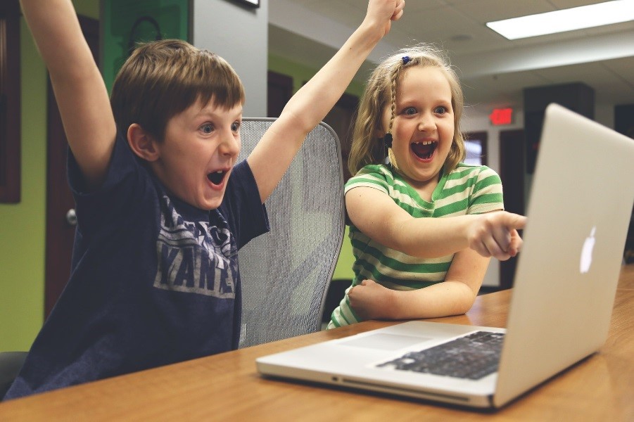 Boy and girl looking at a laptop laughing