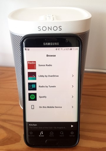 A mobile phone with the Libby app showing next to a Sonos speaker