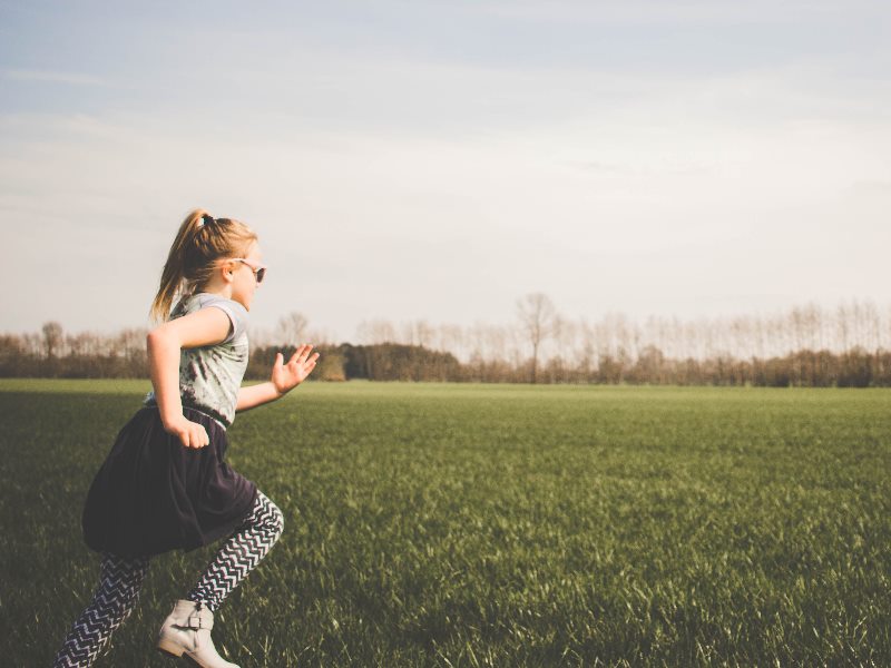 A girl running on a grass playing field