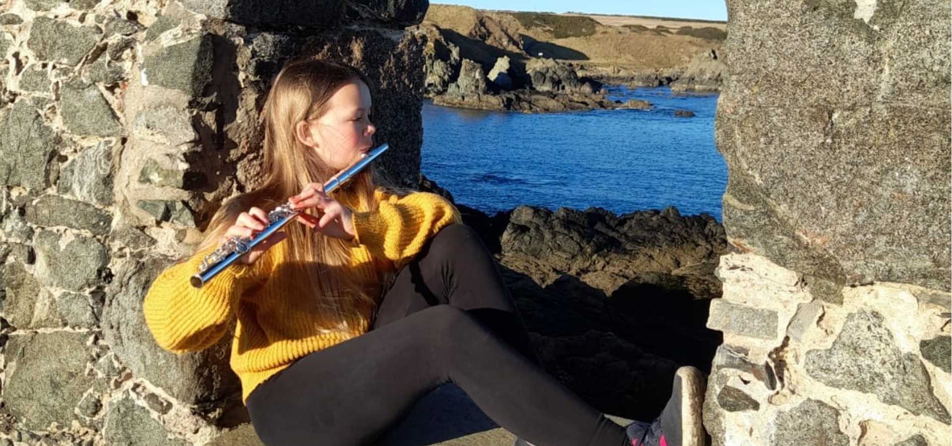 A girl playing a flute outdoors