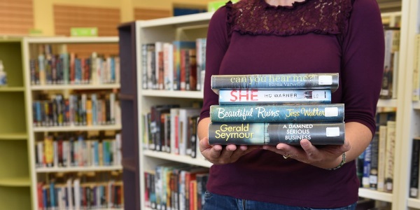 An image of a person holding a pile of books