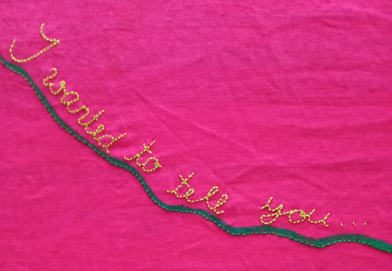 pink tabelcoth with embroidered text with the words "I wanted to tell you... "