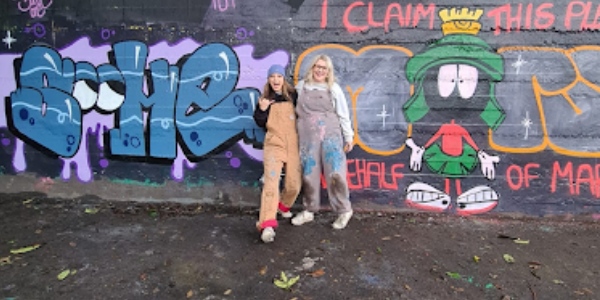 Kirsty and Naomi standing in front of some of their street art