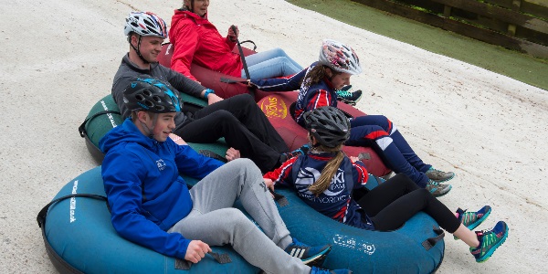 A group of people enjoying a tubing session on the dry ski slope
