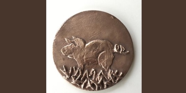 A bronze medallion with an engraved pig
