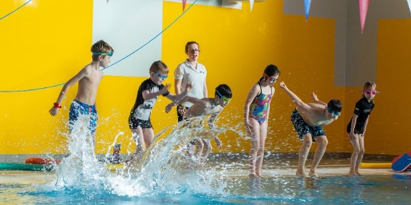 A group of children jumping into the pool